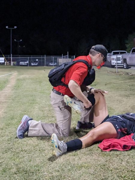 Sanders helps stretch Lady Raider soccer player, Lilly Matherne.