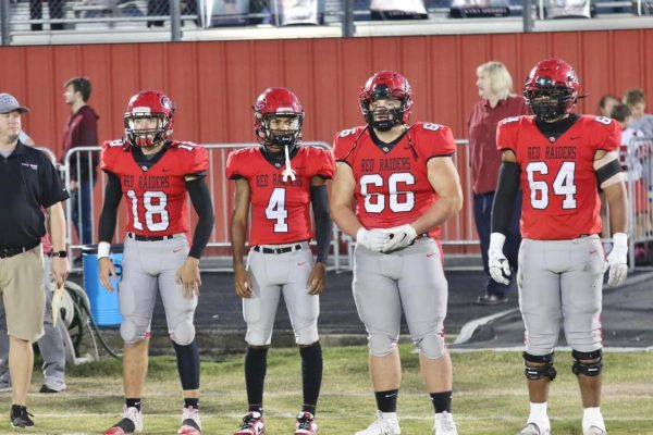 Four Red Raider football players watch on the sidelines during the Homecoming game.