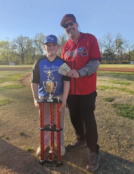 President of the baseball league poses for a photo with home run derby winner, Trey Stevens, with his $300 and trophy.